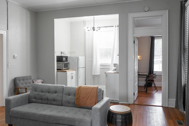 living room featuring crown molding, hardwood / wood-style floors, and a chandelier