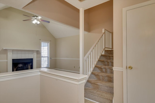 staircase featuring a fireplace, lofted ceiling, and a ceiling fan