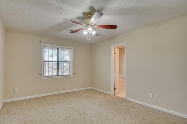 carpeted spare room with ceiling fan, baseboards, and a textured ceiling