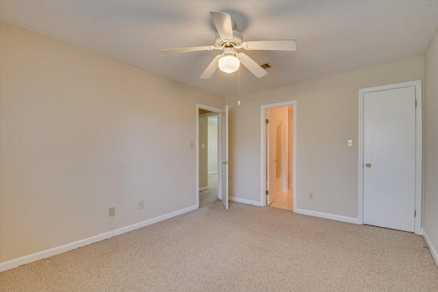 unfurnished bedroom with visible vents, baseboards, ceiling fan, light colored carpet, and a textured ceiling