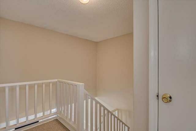 stairs featuring carpet floors and a textured ceiling