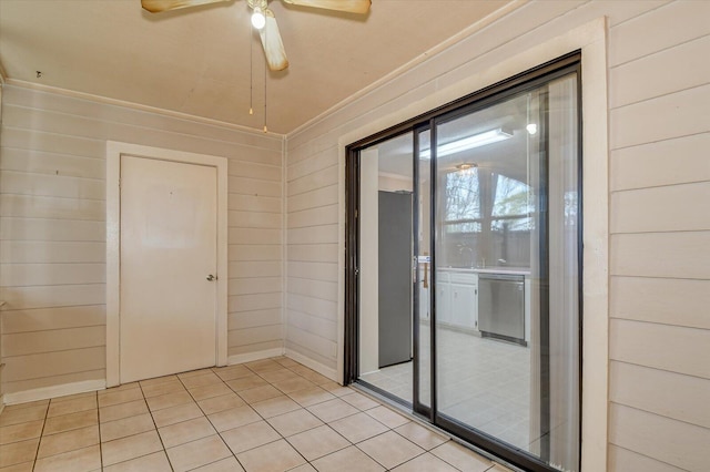 interior space with light tile patterned flooring, wood walls, and ceiling fan