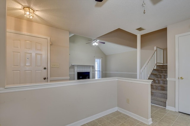 interior space with visible vents, a textured ceiling, a fireplace, lofted ceiling, and ceiling fan