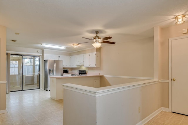 kitchen with visible vents, a peninsula, stainless steel appliances, light countertops, and white cabinets