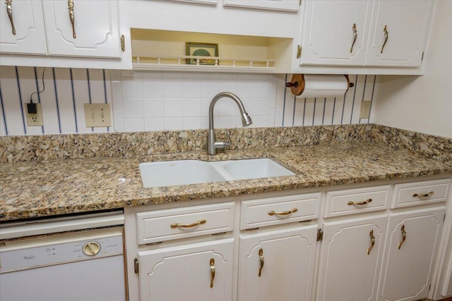 kitchen featuring light stone counters, white cabinetry, tasteful backsplash, a sink, and dishwasher