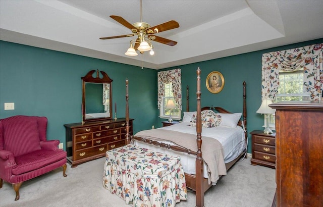 bedroom with a ceiling fan, carpet flooring, and a tray ceiling