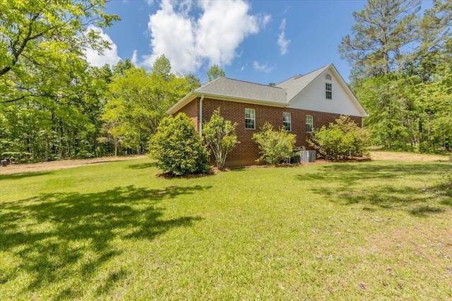view of side of property featuring central AC, brick siding, and a lawn