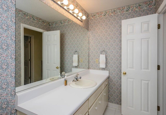 bathroom featuring vanity, wallpapered walls, tile patterned floors, and baseboards