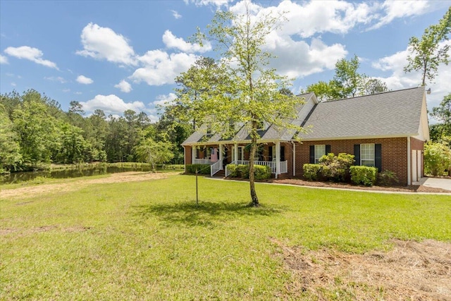 view of front facade with roof with shingles, a front lawn, a porch, and brick siding