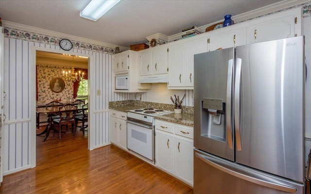 kitchen featuring light wood finished floors, under cabinet range hood, a notable chandelier, crown molding, and white appliances