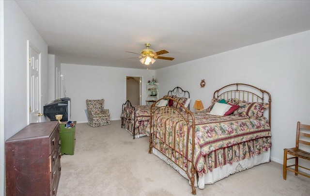 bedroom featuring a wood stove, a ceiling fan, and light colored carpet