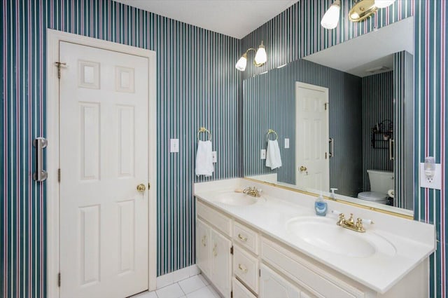 bathroom featuring tile patterned floors, wallpapered walls, toilet, and a sink