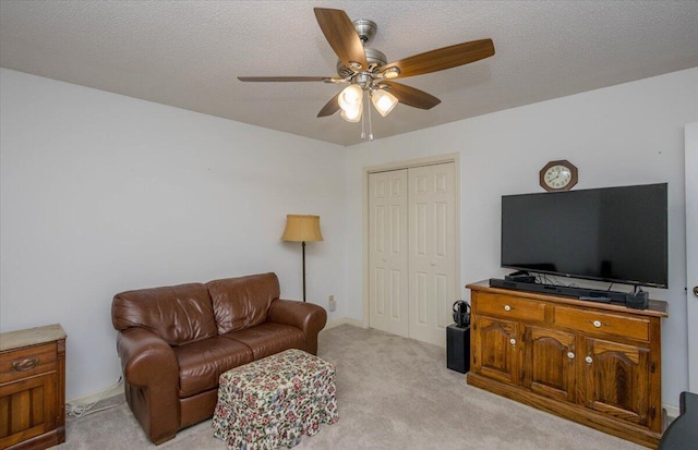 living room with a textured ceiling, ceiling fan, and light carpet