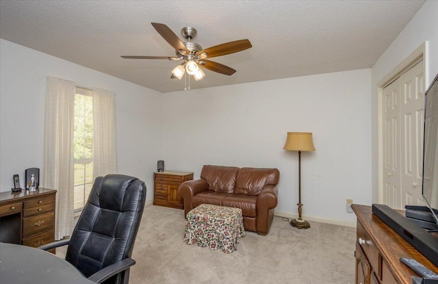 home office featuring a textured ceiling, ceiling fan, baseboards, and light carpet