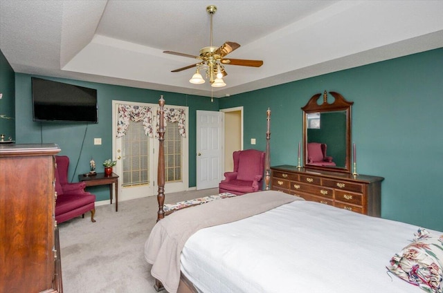 carpeted bedroom featuring a raised ceiling and a ceiling fan