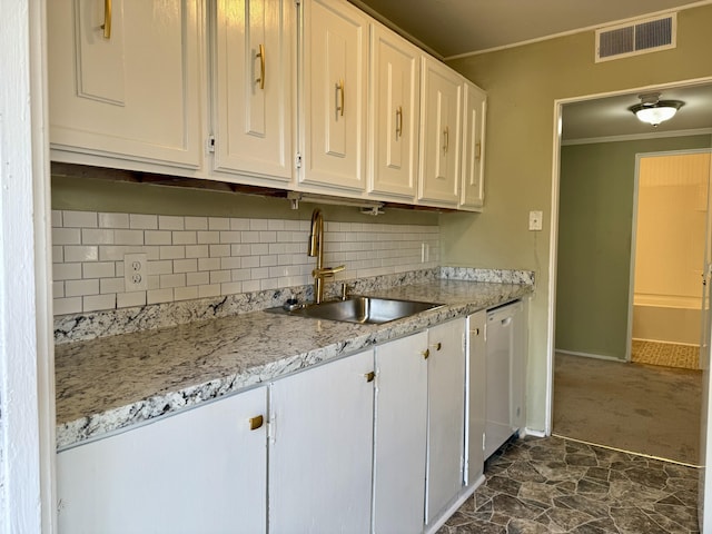 kitchen featuring tasteful backsplash, white cabinets, a sink, visible vents, and crown molding