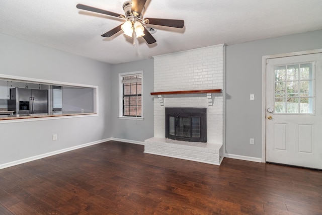 unfurnished living room featuring a textured ceiling, ceiling fan, a fireplace, and dark hardwood / wood-style floors