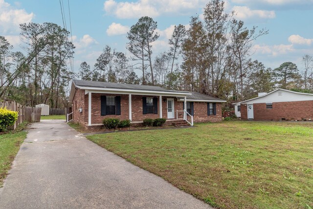 single story home featuring an outbuilding, covered porch, and a front yard