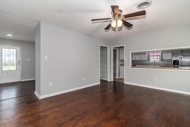 unfurnished living room featuring a textured ceiling, dark hardwood / wood-style floors, and ceiling fan