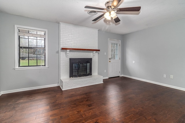 unfurnished living room featuring a fireplace, a textured ceiling, dark hardwood / wood-style floors, and ceiling fan