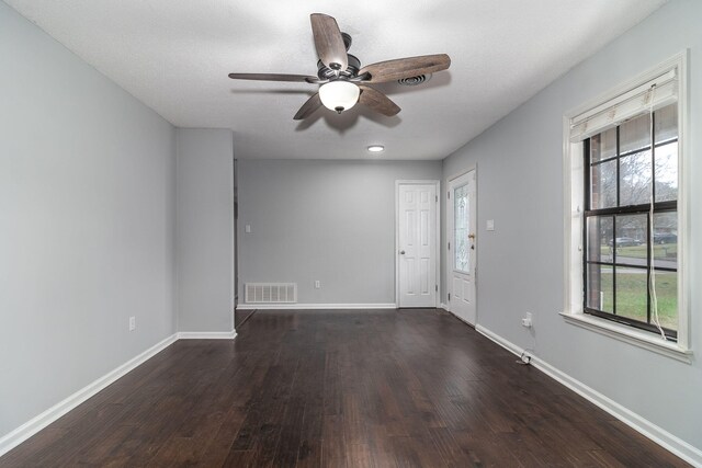 unfurnished room with a textured ceiling, ceiling fan, and dark wood-type flooring