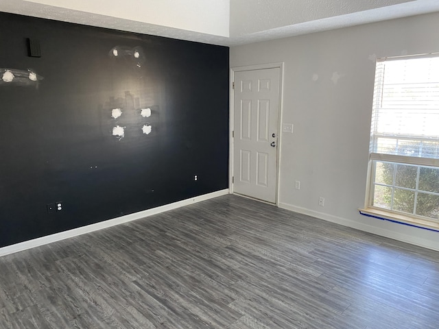 unfurnished room featuring a textured ceiling, dark hardwood / wood-style flooring, and a wealth of natural light