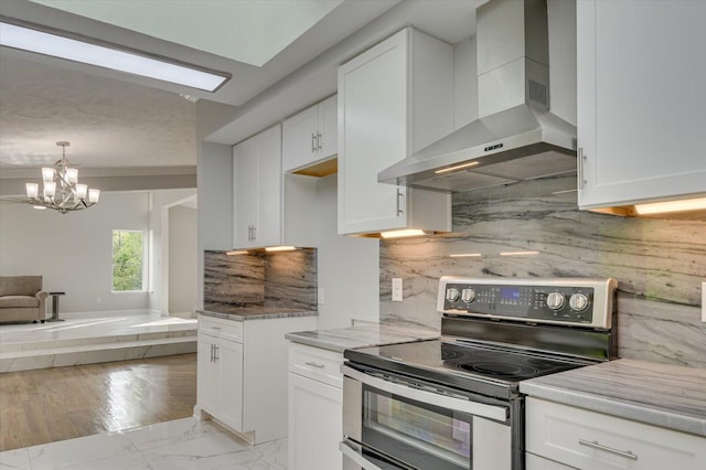 2417 Wilkshire Dr, Augusta, GA 30904 - kitchen featuring open floor plan, white cabinetry, a chandelier, electric stove, and wall chimney range hood