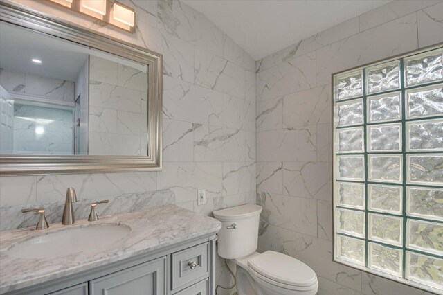 2417 Wilkshire Dr, Augusta, GA 30904 - bathroom with tile walls, toilet, vanity, a healthy amount of sunlight, and vaulted ceiling