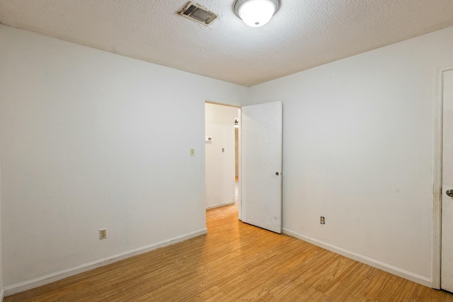 unfurnished room featuring light hardwood / wood-style floors and a textured ceiling