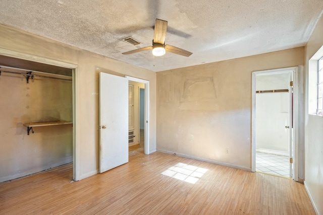 unfurnished bedroom with ceiling fan, a closet, light hardwood / wood-style floors, and a textured ceiling