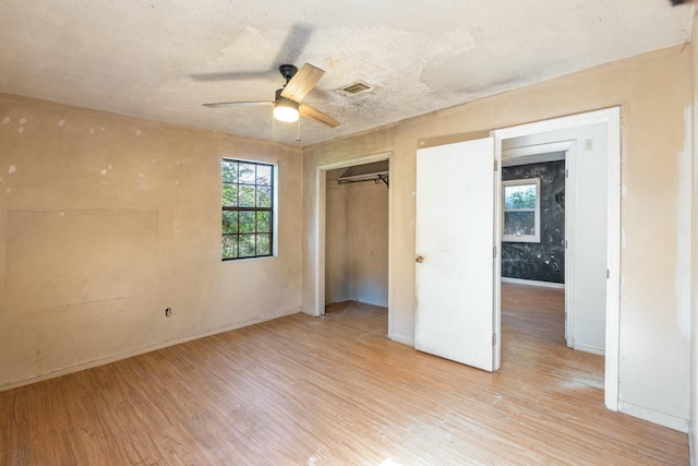 unfurnished bedroom with ceiling fan, a closet, light hardwood / wood-style flooring, and a textured ceiling