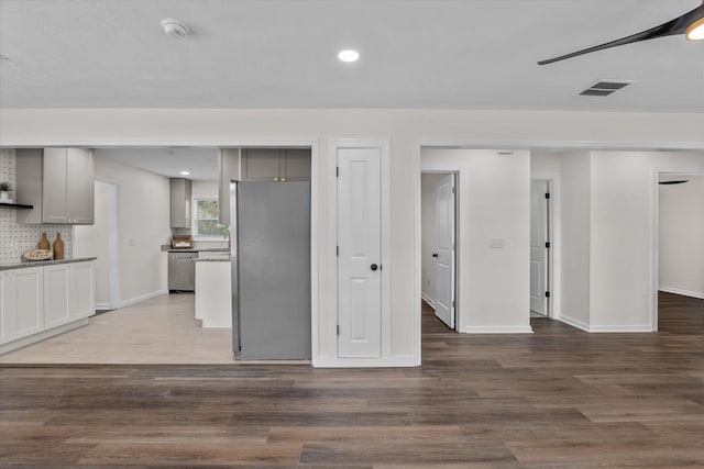 kitchen with gray cabinetry, tasteful backsplash, stainless steel appliances, and hardwood / wood-style floors