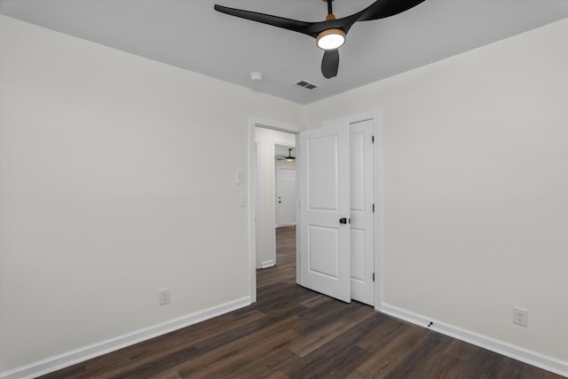 unfurnished bedroom with ceiling fan and dark wood-type flooring