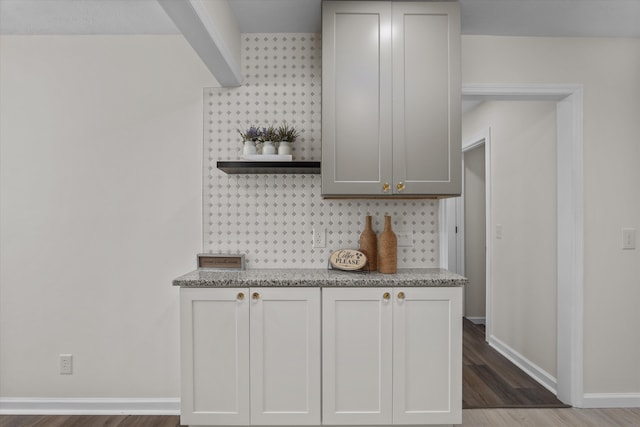 kitchen featuring tasteful backsplash, white cabinetry, dark hardwood / wood-style flooring, and light stone countertops