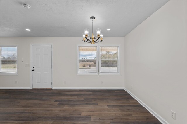 unfurnished dining area with a notable chandelier, dark wood-type flooring, and a wealth of natural light