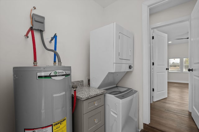 washroom with electric water heater, dark hardwood / wood-style floors, and stacked washer / dryer