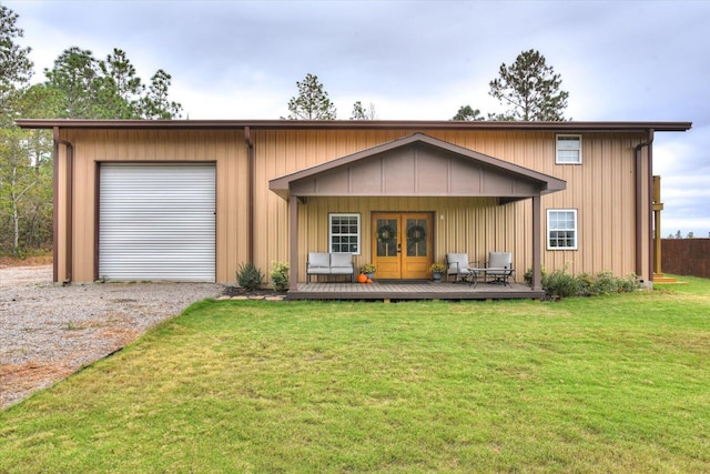 view of front of house featuring a wooden deck, french doors, a front yard, and a garage