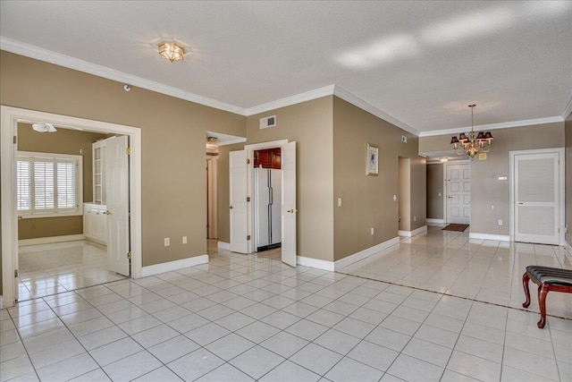 tiled empty room featuring ornamental molding, a textured ceiling, and an inviting chandelier