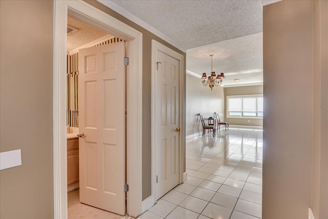 corridor with a textured ceiling, a notable chandelier, and light tile patterned flooring