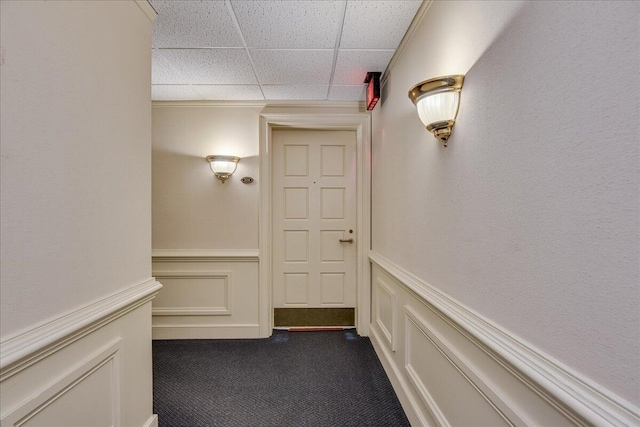 hall featuring a drop ceiling and dark carpet