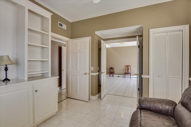 corridor featuring a textured ceiling, built in features, and ornamental molding