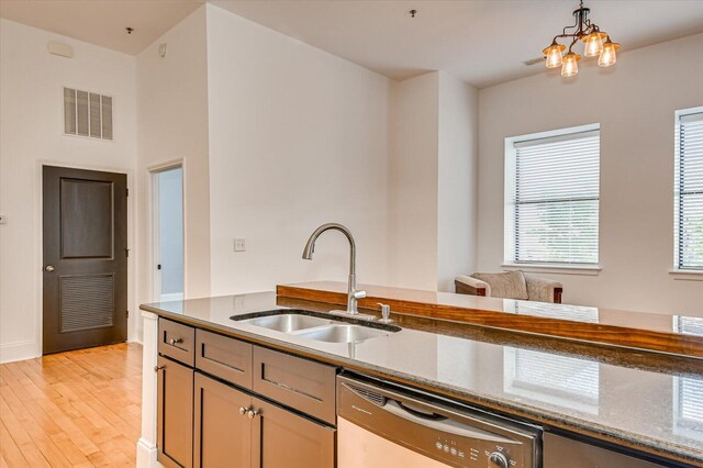 kitchen with dishwasher, sink, hanging light fixtures, light hardwood / wood-style flooring, and a chandelier