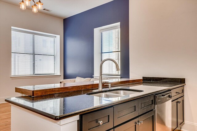 kitchen with kitchen peninsula, stainless steel dishwasher, a healthy amount of sunlight, and sink