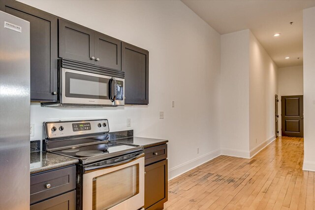 kitchen with dark brown cabinets, light wood-type flooring, and appliances with stainless steel finishes