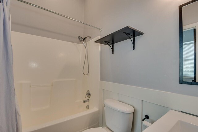 bathroom with shower / bathing tub combination, toilet, and tile walls