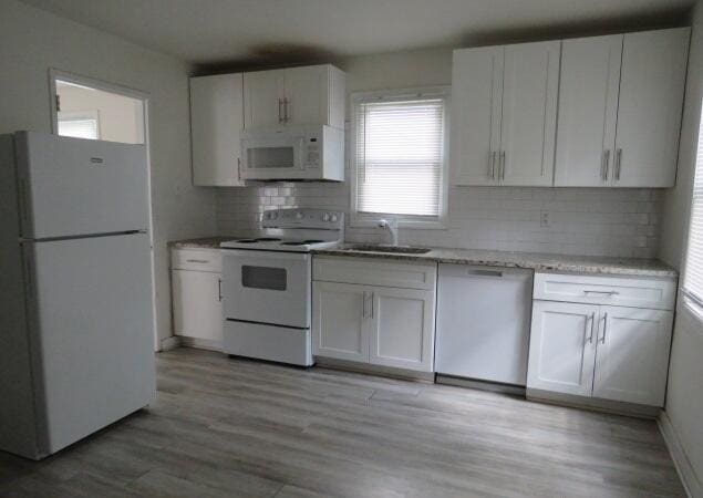 2320 Getzen St, Augusta, GA 30906 - kitchen featuring white appliances, decorative backsplash, white cabinetry, and light wood-style floors