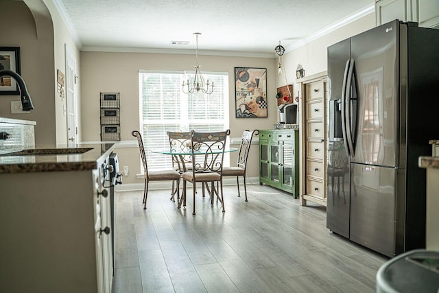 1410 Summit Way, Grovetown, GA 30813 - kitchen featuring stainless steel fridge, light wood-style floors, dark countertops, crown molding, and a chandelier