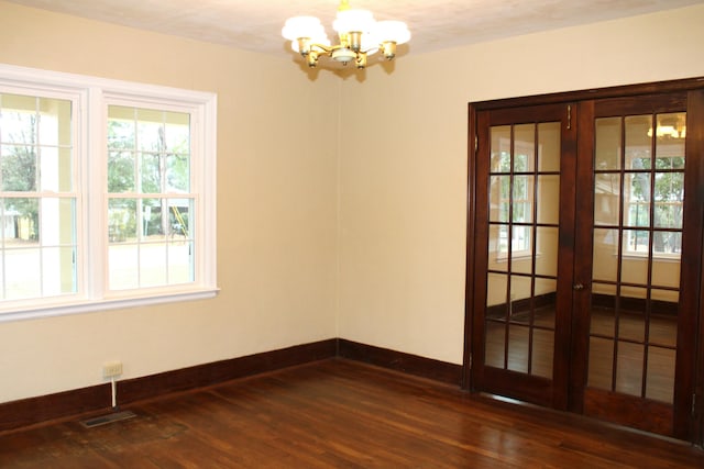 spare room with a notable chandelier and dark hardwood / wood-style floors