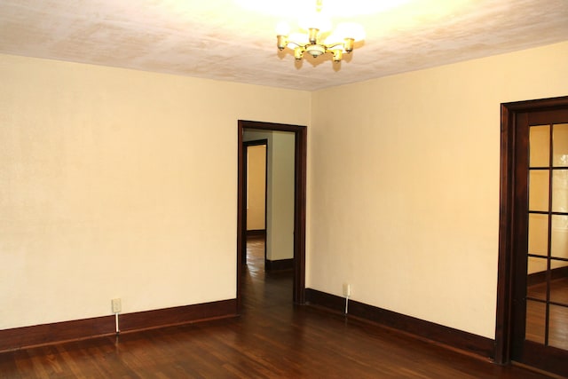 unfurnished room with a textured ceiling, a notable chandelier, and dark hardwood / wood-style flooring