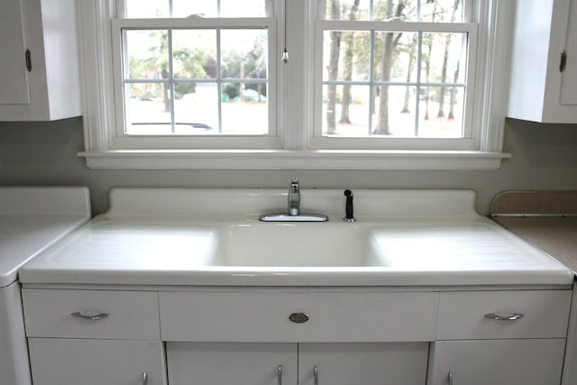 room details featuring white cabinetry, washer / dryer, and sink